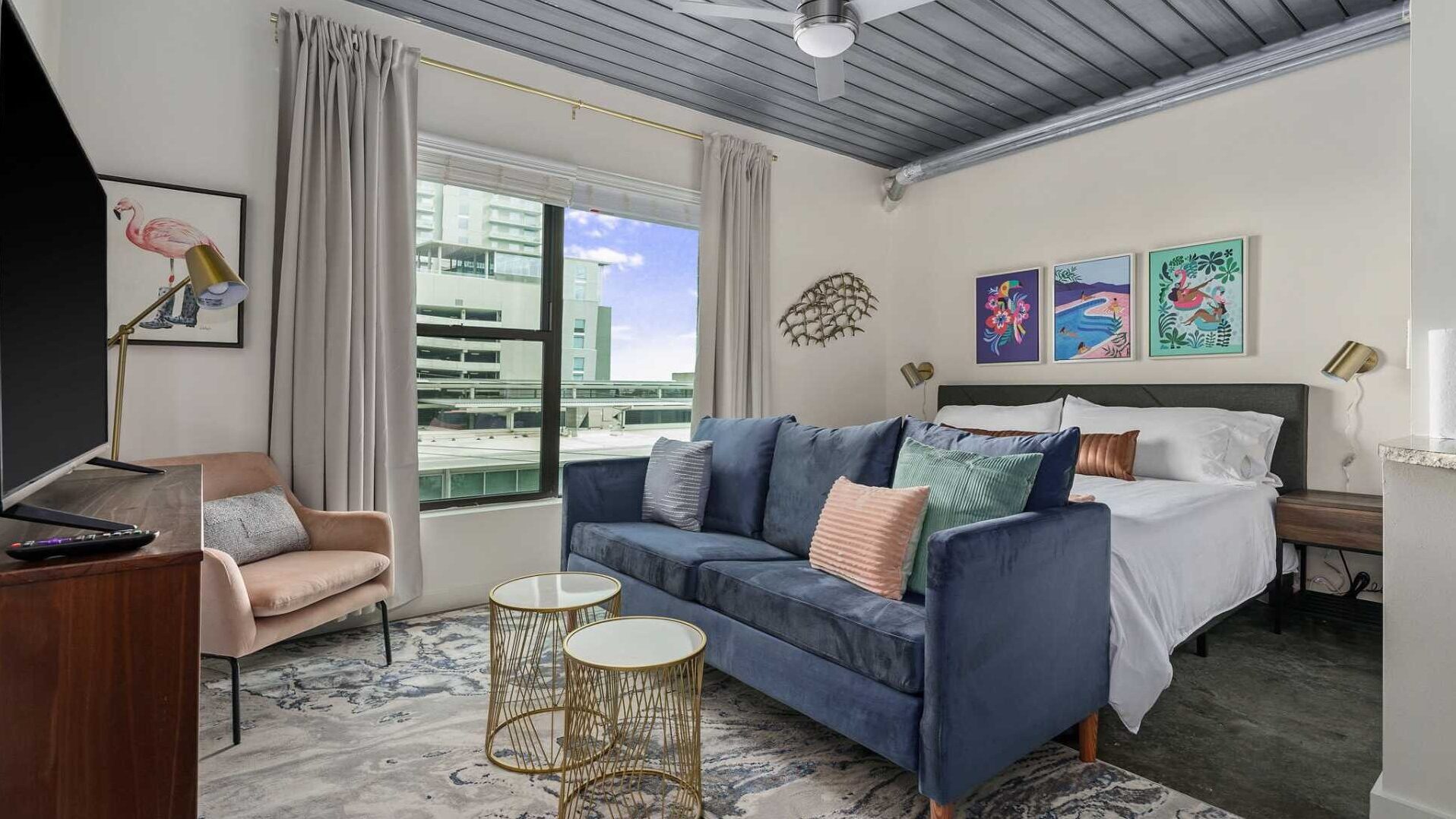 A cozy bedroom with a huge window and a blue couch