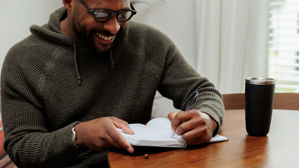 man writing in a notebook in a Lodgeur fully furnished apartment