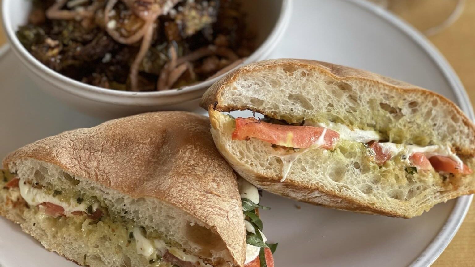 A plate with a sandwich and a bowl of pasta