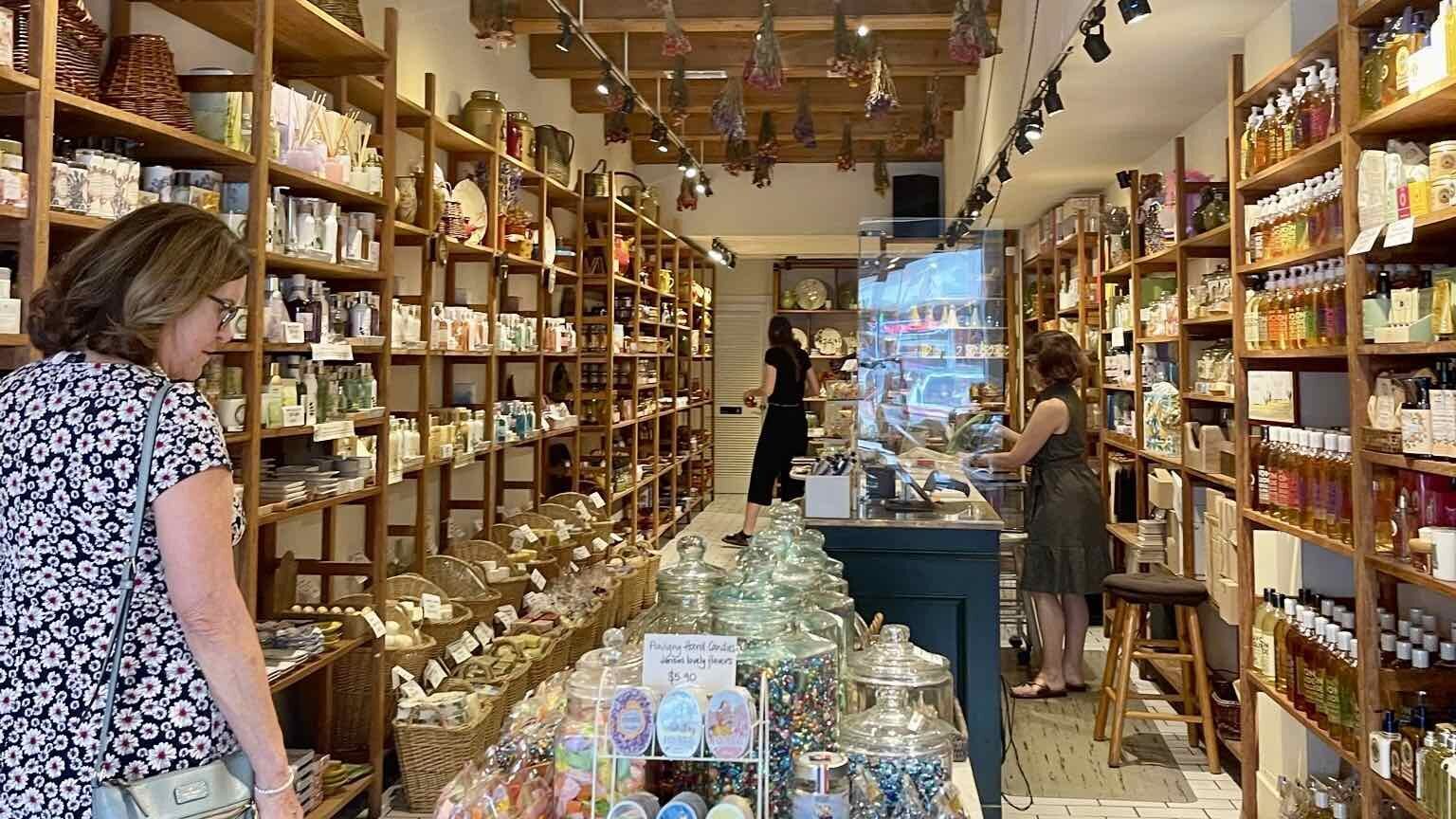 A woman browsing through shelves of food and other items in a store.