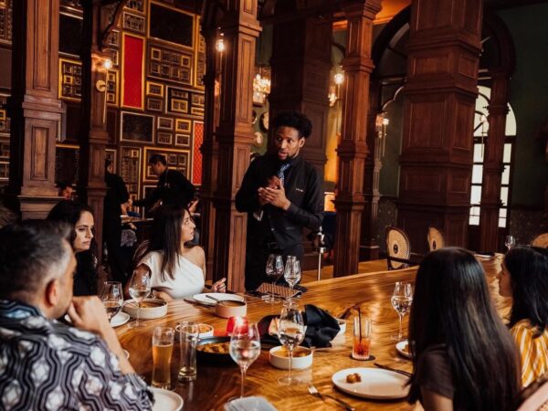 group of people eating dinner while talking to the waiter